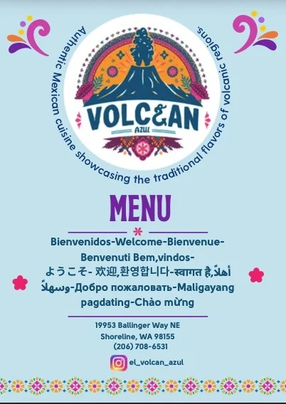 El Volcán Azul multilingual blue menu cover with its volcano logo, welcome lines, Shoreline address, phone number, Instagram handle, and floral border